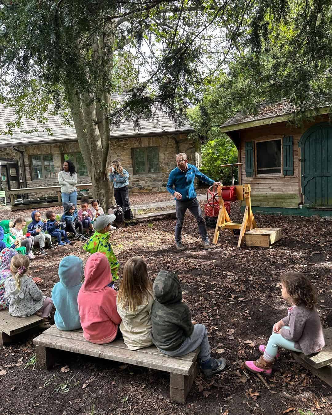 kids learning outside from male demonstrator on fieldtrip